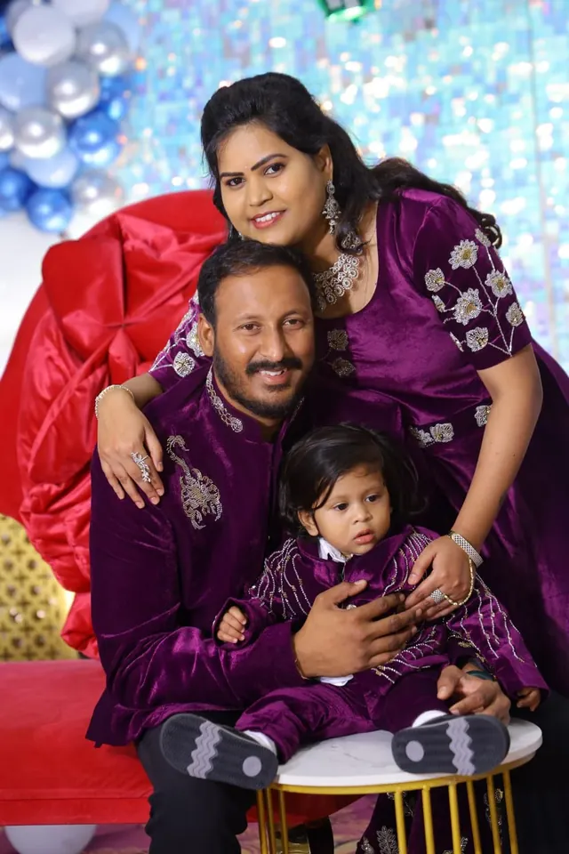 Parents and their young son in matching plum occasion wear with silver embroidery