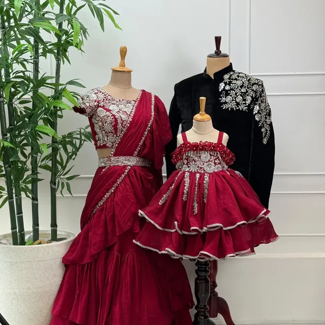 A red pre-draped ruffle saree, black velvet bandhgala with silver embroidery and a red ruffled frock on dress forms
